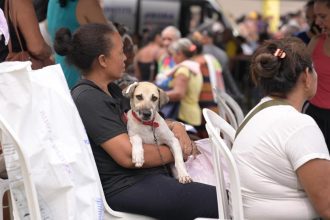 Mulher sentada com cachorro no colo em evento de castração.
