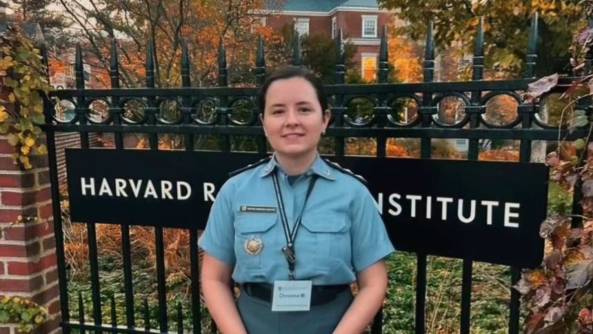 Oficial da Polícia Militar do Amazona ssorrindo em frente ao portão do Harvard Radcliffe Institute, usando uniforme.