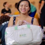 Mulher sorrindo segura Kit Bebê Amazonas, iniciativa para gestantes em vulnerabilidade.