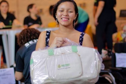 Mulher sorrindo segura Kit Bebê Amazonas, iniciativa para gestantes em vulnerabilidade.