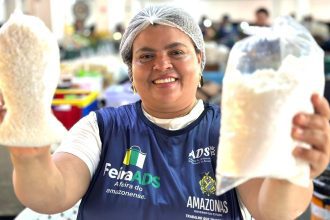 Mulher sorrindo segura sacos de grãos em feira regional de Manaus