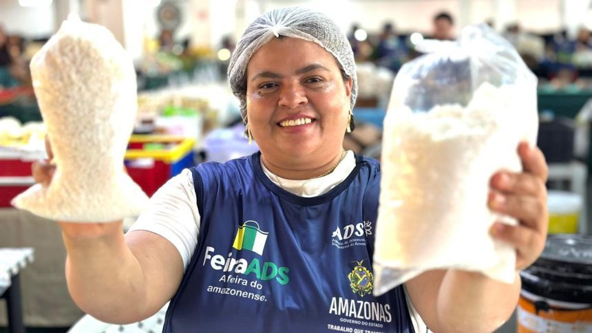 Mulher sorrindo segura sacos de grãos em feira regional de Manaus