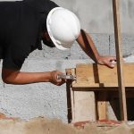 Pedreiro trabalhando em uma obra de construção com ferramentas e madeiramento