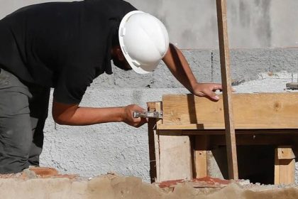 Pedreiro trabalhando em uma obra de construção com ferramentas e madeiramento