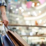 Pessoa com sacolas de compras em shopping center.
