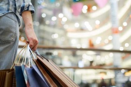 Pessoa com sacolas de compras em shopping center.