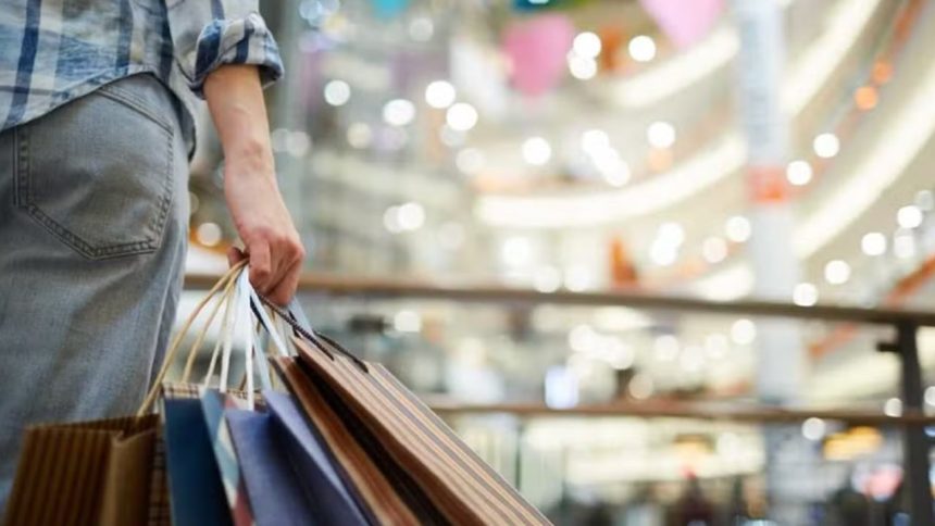 Pessoa com sacolas de compras em shopping center.