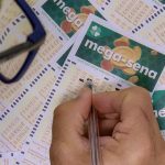 Pessoa preenchendo um bilhete da Mega-Sena com uma caneta.