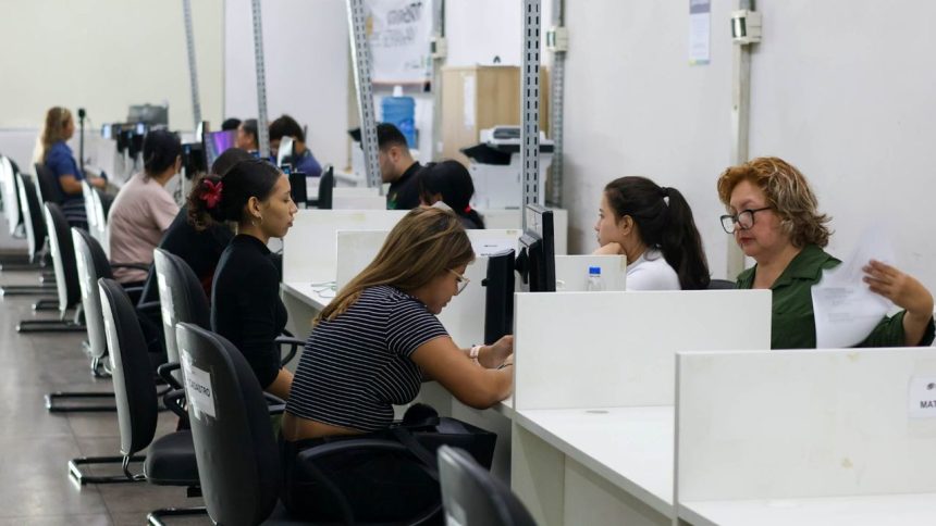 Pessoas em postos de atendimento, provavelmente em um local de trabalho ou escritório, com computadores.