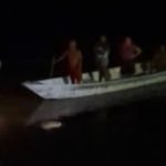 Pessoas em um barco no Rio Negro à noite.