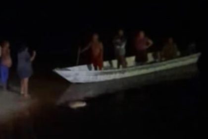 Pessoas em um barco no Rio Negro à noite.