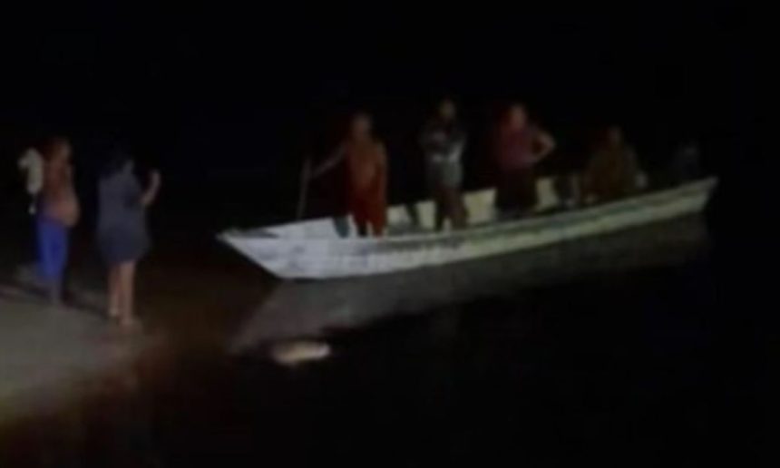 Pessoas em um barco no Rio Negro à noite.