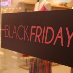 Placa de Black Friday em loja, com texto em rosa sobre fundo marrom.