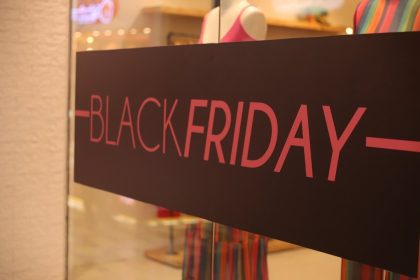 Placa de Black Friday em loja, com texto em rosa sobre fundo marrom.