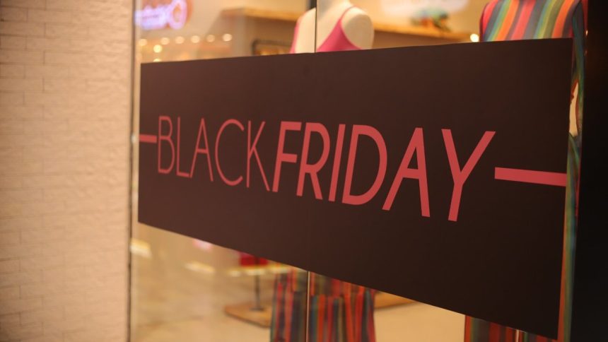 Placa de Black Friday em loja, com texto em rosa sobre fundo marrom.