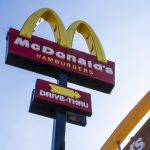 Placa do McDonald's com logotipo e letreiro 'Drive-Thru' em um dia ensolarado.