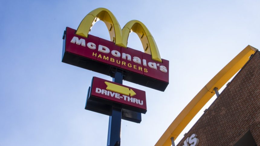 Placa do McDonald's com logotipo e letreiro 'Drive-Thru' em um dia ensolarado.