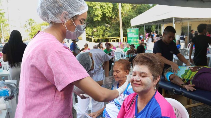 Profissional de saúde aplicando tratamento facial em mulher durante o Arena Rosa Azul, com outras pessoas ao fundo.