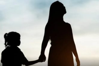 Silhueta de mãe e filha de mãos dadas, com céu ao fundo.