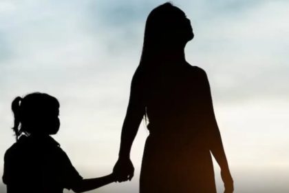 Silhueta de mãe e filha de mãos dadas, com céu ao fundo.