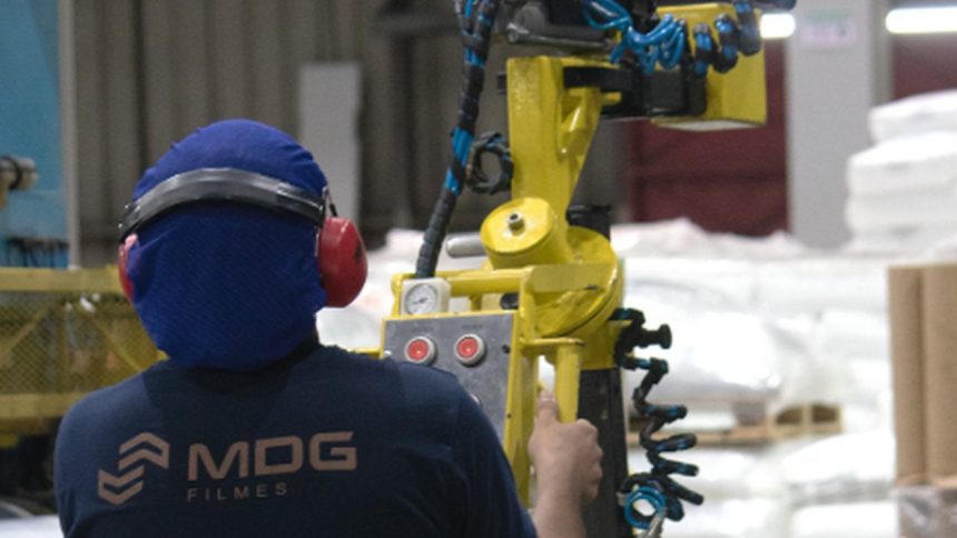 Técnico da MDG Filmes operando equipamento em fábrica