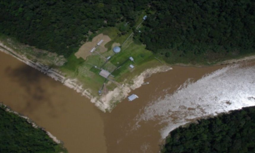Vista aérea da confluência de rios na Amazônia, com edifícios e vegetação densa.