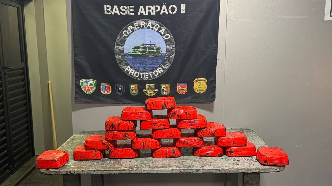 Apresentação de apreensão de drogas pela Polícia Civil do Amazonas. Blocos vermelhos empilhados sobre uma mesa.