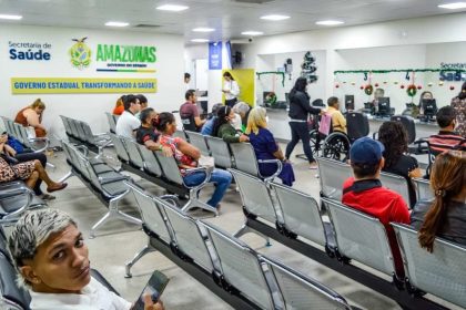 Sala de espera com pessoas sentadas em cadeiras de metal, aguardando atendimento em um centro de saúde.