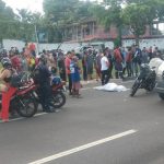 Acidente de trânsito com ambulância e pessoas reunidas. Motos e carro na cena.