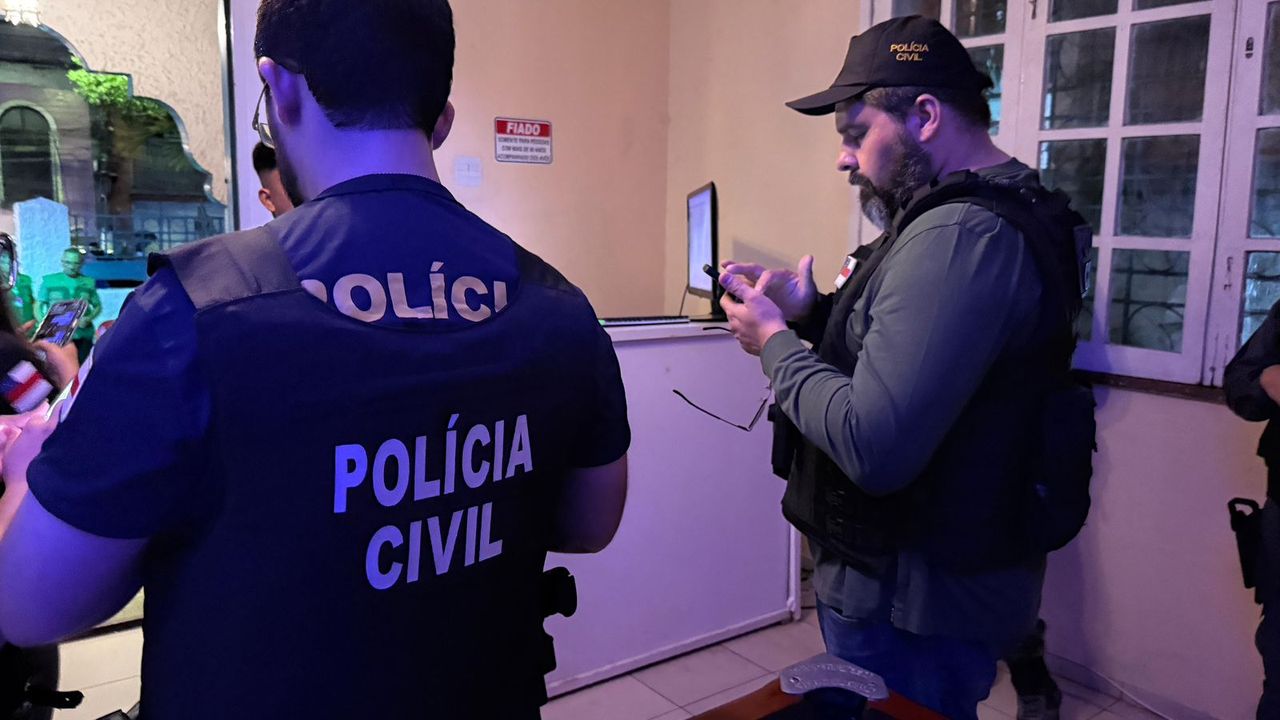 Policiais civis em ação, investigando em ambiente interno. Homens fardados e equipamentos.