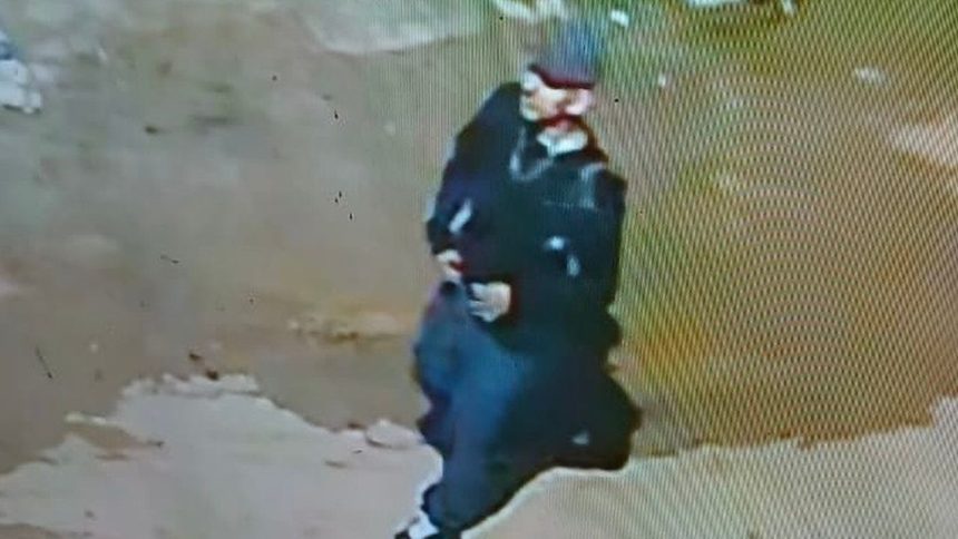 Imagem de segurança mostrando pessoa vestindo roupas escuras e chapéu.