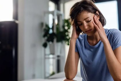 Mulher com dor de cabeça massageando as têmporas