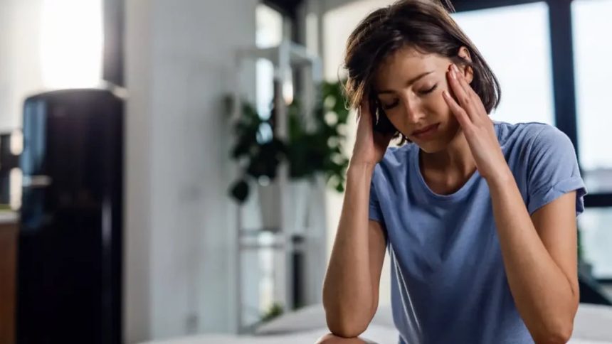 Mulher com dor de cabeça massageando as têmporas