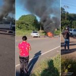 Acidente de trânsito: carro e moto em chamas após colisão, fumaça preta no céu e pessoas no local.