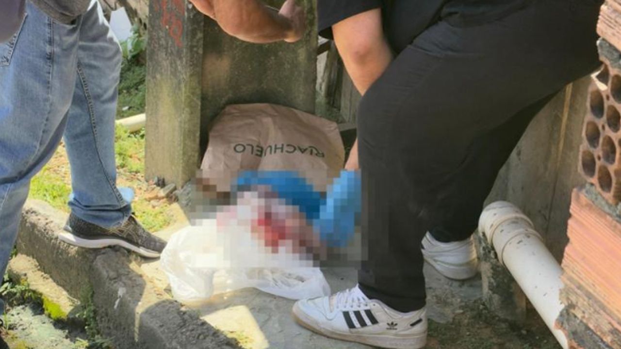 Cena de crime com recém-nascida em sacolas e pessoas no local, imagem borrada para preservar detalhes.