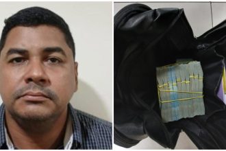 Policial Militar do Amazonas ao lado de mala preta aberta com maços de dinheiro amarrados.