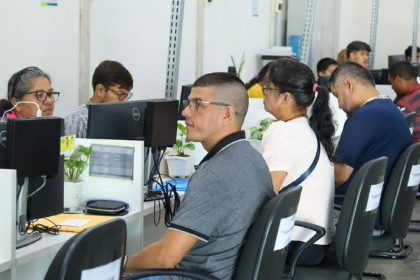 Pessoas sentadas em seus computadores em um ambiente de escritório, um local de atendimento e busca de emprego do Sine.