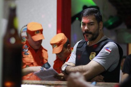 Policiais em ação em um ambiente interno, com oficiais dos Bombeiros uniformizados.