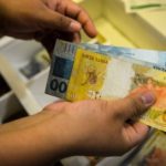 Salário mínimo pode chegar a R$ 1.717 em 2027 O Governo Federal encaminhou ao Congresso Nacional, na quarta-feira (15), o Projeto de Lei de Diretrizes Orçamentárias (PLDO) de 2027 com a previsão de que o salário mínimo alcance R$ 1.717 no próximo ano. O valor representa um aumento nominal de 5,92% em relação ao piso atual. A estimativa segue a política de reajuste que considera a soma da inflação medida pelo Índice Nacional de Preços ao Consumidor (INPC) e o desempenho do Produto Interno Bruto (PIB) de dois anos anteriores. Para o cálculo apresentado, a inflação projetada é de 3,06%, enquanto o crescimento da economia em 2025 foi estimado em 2,3%. O cálculo também observa as regras do arcabouço fiscal em vigor, que estabelece limites para o crescimento das despesas públicas. Pelo modelo atual, o aumento real do salário mínimo — acima da inflação — deve respeitar um intervalo de expansão de gastos entre 0,6% e 2,5% ao ano. Como o crescimento do PIB ficou dentro do teto permitido pelo regime fiscal, o índice poderá ser aplicado integralmente na definição do novo valor. A proposta ainda será analisada pelo Congresso Nacional, etapa em que o texto pode sofrer alterações antes de sua aprovação final.