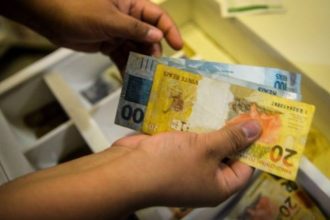 Salário mínimo pode chegar a R$ 1.717 em 2027 O Governo Federal encaminhou ao Congresso Nacional, na quarta-feira (15), o Projeto de Lei de Diretrizes Orçamentárias (PLDO) de 2027 com a previsão de que o salário mínimo alcance R$ 1.717 no próximo ano. O valor representa um aumento nominal de 5,92% em relação ao piso atual. A estimativa segue a política de reajuste que considera a soma da inflação medida pelo Índice Nacional de Preços ao Consumidor (INPC) e o desempenho do Produto Interno Bruto (PIB) de dois anos anteriores. Para o cálculo apresentado, a inflação projetada é de 3,06%, enquanto o crescimento da economia em 2025 foi estimado em 2,3%. O cálculo também observa as regras do arcabouço fiscal em vigor, que estabelece limites para o crescimento das despesas públicas. Pelo modelo atual, o aumento real do salário mínimo — acima da inflação — deve respeitar um intervalo de expansão de gastos entre 0,6% e 2,5% ao ano. Como o crescimento do PIB ficou dentro do teto permitido pelo regime fiscal, o índice poderá ser aplicado integralmente na definição do novo valor. A proposta ainda será analisada pelo Congresso Nacional, etapa em que o texto pode sofrer alterações antes de sua aprovação final.