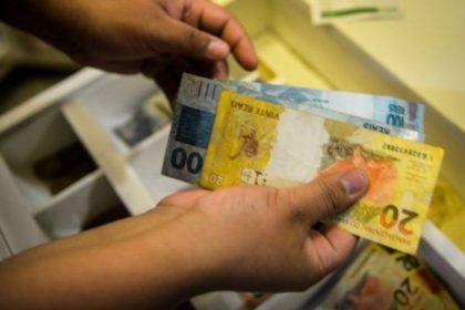 Salário mínimo pode chegar a R$ 1.717 em 2027 O Governo Federal encaminhou ao Congresso Nacional, na quarta-feira (15), o Projeto de Lei de Diretrizes Orçamentárias (PLDO) de 2027 com a previsão de que o salário mínimo alcance R$ 1.717 no próximo ano. O valor representa um aumento nominal de 5,92% em relação ao piso atual. A estimativa segue a política de reajuste que considera a soma da inflação medida pelo Índice Nacional de Preços ao Consumidor (INPC) e o desempenho do Produto Interno Bruto (PIB) de dois anos anteriores. Para o cálculo apresentado, a inflação projetada é de 3,06%, enquanto o crescimento da economia em 2025 foi estimado em 2,3%. O cálculo também observa as regras do arcabouço fiscal em vigor, que estabelece limites para o crescimento das despesas públicas. Pelo modelo atual, o aumento real do salário mínimo — acima da inflação — deve respeitar um intervalo de expansão de gastos entre 0,6% e 2,5% ao ano. Como o crescimento do PIB ficou dentro do teto permitido pelo regime fiscal, o índice poderá ser aplicado integralmente na definição do novo valor. A proposta ainda será analisada pelo Congresso Nacional, etapa em que o texto pode sofrer alterações antes de sua aprovação final.