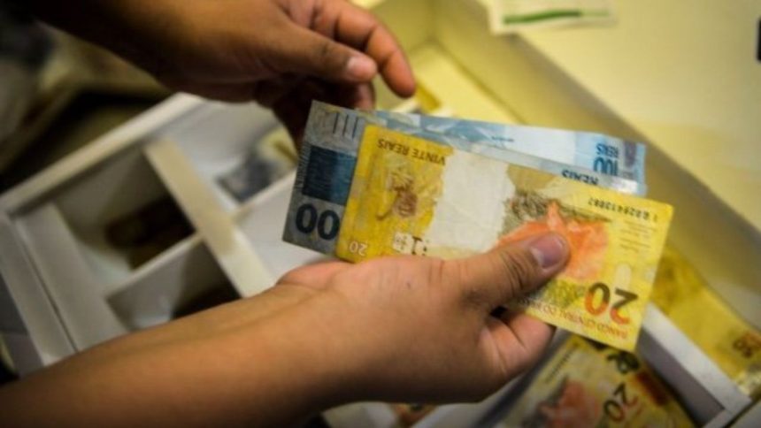 Salário mínimo pode chegar a R$ 1.717 em 2027 O Governo Federal encaminhou ao Congresso Nacional, na quarta-feira (15), o Projeto de Lei de Diretrizes Orçamentárias (PLDO) de 2027 com a previsão de que o salário mínimo alcance R$ 1.717 no próximo ano. O valor representa um aumento nominal de 5,92% em relação ao piso atual. A estimativa segue a política de reajuste que considera a soma da inflação medida pelo Índice Nacional de Preços ao Consumidor (INPC) e o desempenho do Produto Interno Bruto (PIB) de dois anos anteriores. Para o cálculo apresentado, a inflação projetada é de 3,06%, enquanto o crescimento da economia em 2025 foi estimado em 2,3%. O cálculo também observa as regras do arcabouço fiscal em vigor, que estabelece limites para o crescimento das despesas públicas. Pelo modelo atual, o aumento real do salário mínimo — acima da inflação — deve respeitar um intervalo de expansão de gastos entre 0,6% e 2,5% ao ano. Como o crescimento do PIB ficou dentro do teto permitido pelo regime fiscal, o índice poderá ser aplicado integralmente na definição do novo valor. A proposta ainda será analisada pelo Congresso Nacional, etapa em que o texto pode sofrer alterações antes de sua aprovação final.