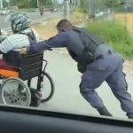Policiais ajudam homem que usa cadeira de rodas a subir ladeira