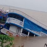 Barco parcialmente submerso em rio, com inclinação acentuada em Manacapuru