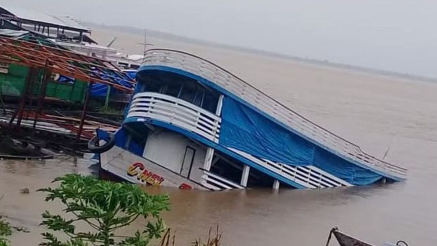 Barco parcialmente submerso em rio, com inclinação acentuada em Manacapuru