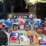 Cestas de Páscoa com ovos de chocolate decorados, barras de chocolate e mochila preta sobre a mesa.