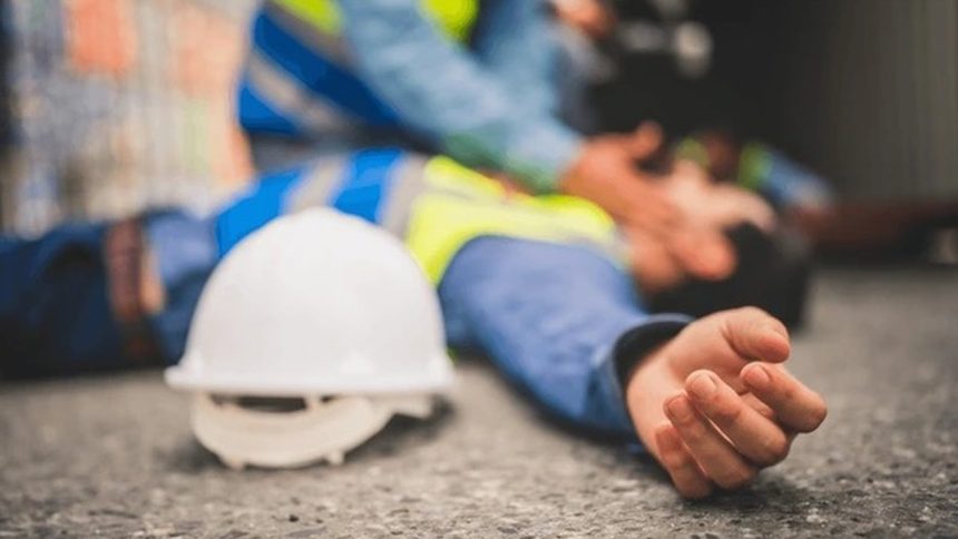 Acidente de trabalho: trabalhador ferido no chão, com capacete próximo e outros funcionários prestando socorro.