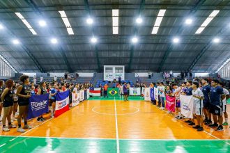 Cerimônia de abertura dos Jogos Universitários do Amazonas com bandeiras e equipes em quadra.