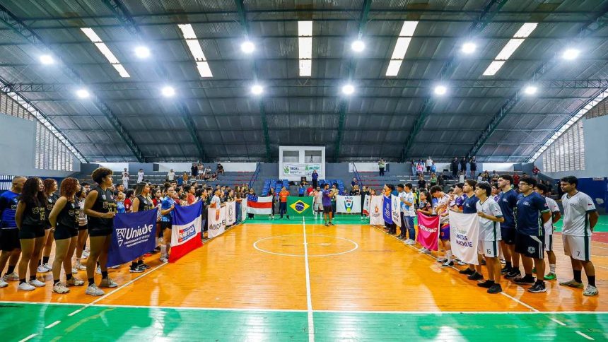Cerimônia de abertura dos Jogos Universitários do Amazonas com bandeiras e equipes em quadra.