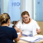 Duas mulheres em escritório oo Procon-AM analisando documentos. Uma delas usa óculos e veste branco.